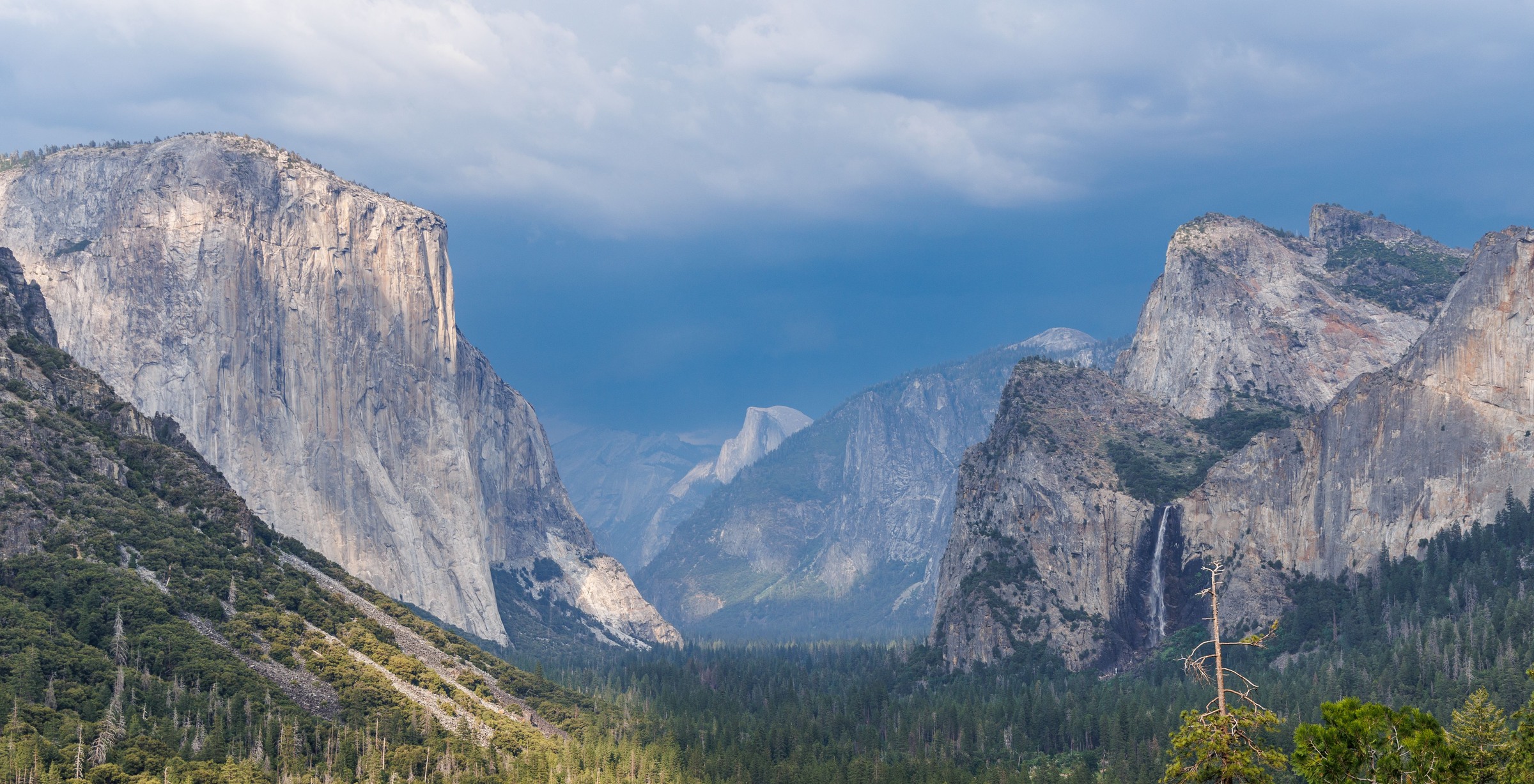 Yosemite Valley granite walls and Bridalveil Fall beneath dark clouds
