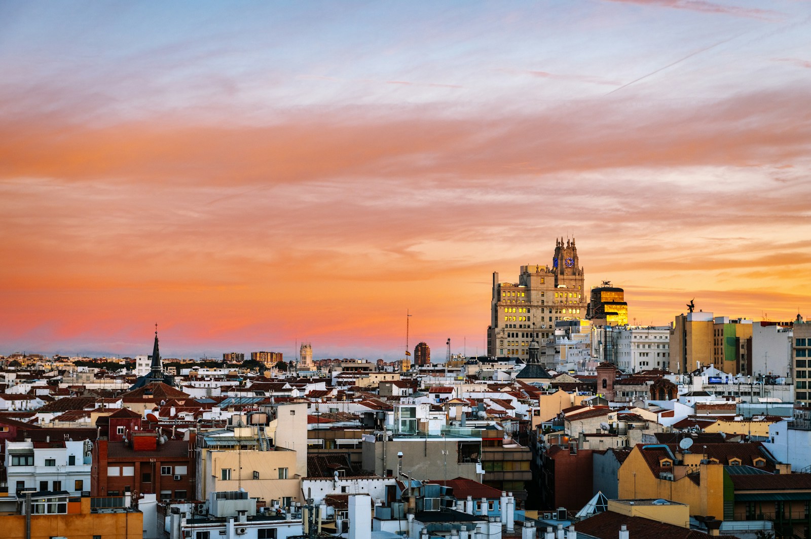 Madrid rooftops and Telefónica Building beneath orange and violet sunset clouds