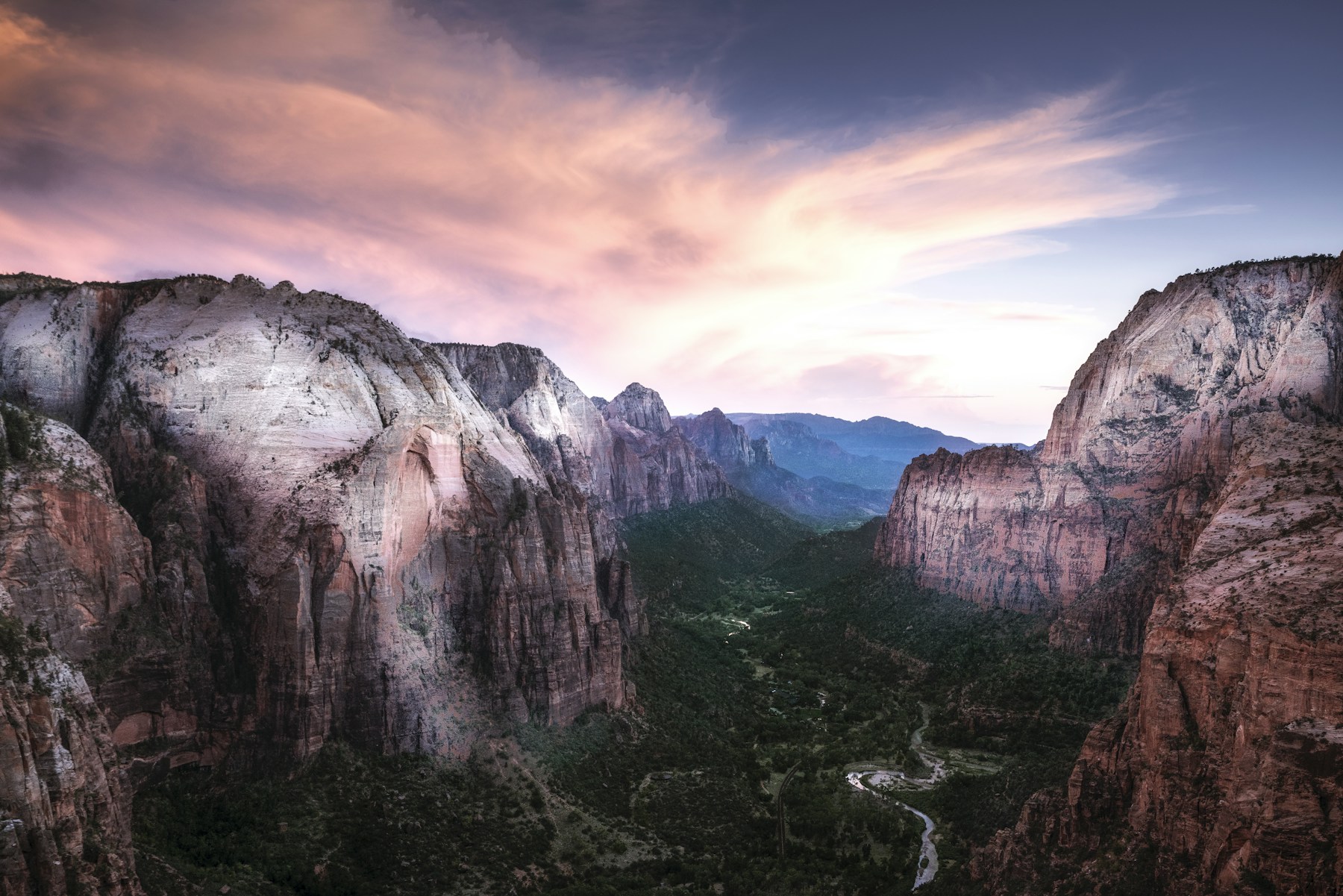 Sunset over Zion Canyon from Angels Landing, with pale sandstone cliffs and a winding river below