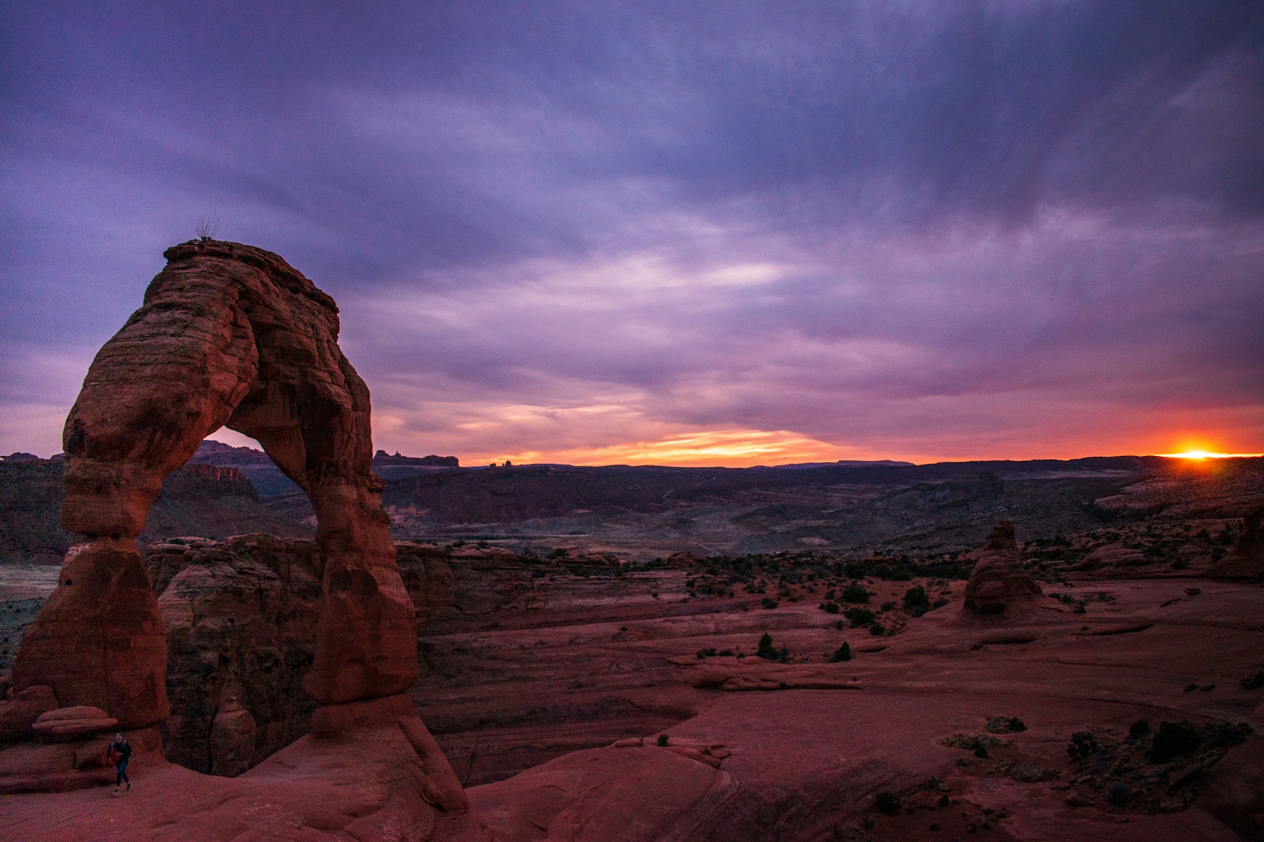 Delicate Arch silhouetted against a purple and orange sunset in Arches National Park