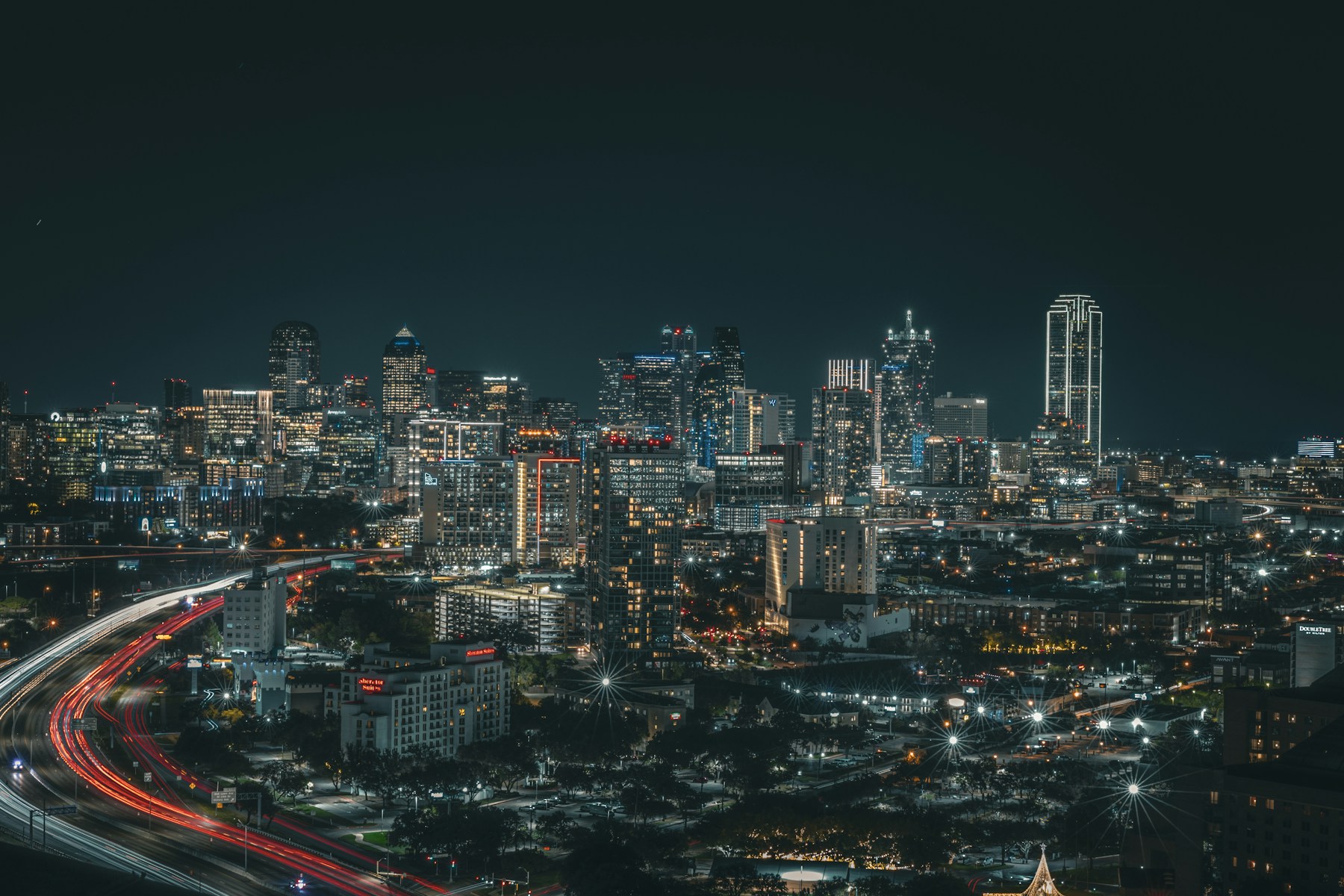 Dallas skyline at night with highway light trails