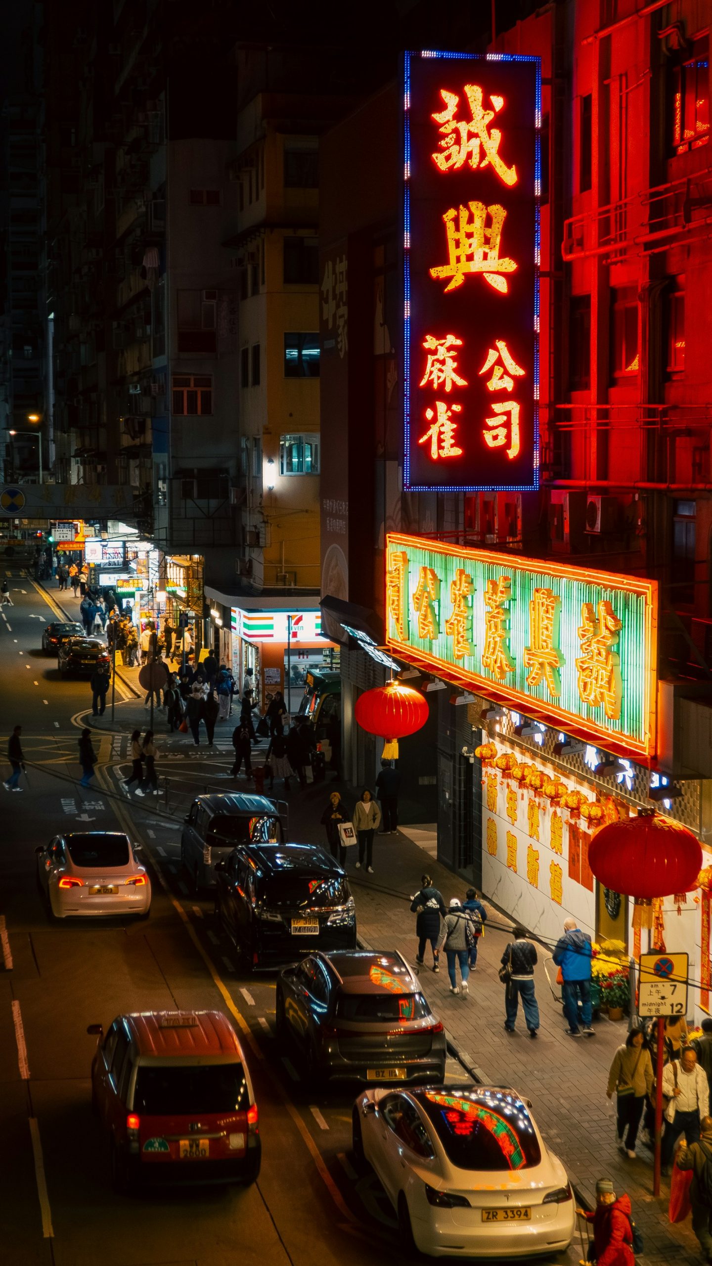 Mong Kok street at night with glowing mahjong school signs, lanterns and pedestrians