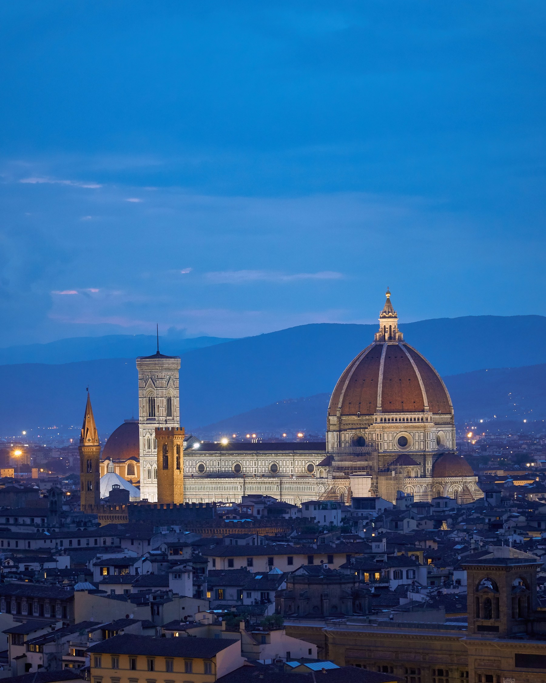 Florence Cathedral dome and Giotto bell tower glowing against blue-hour sky