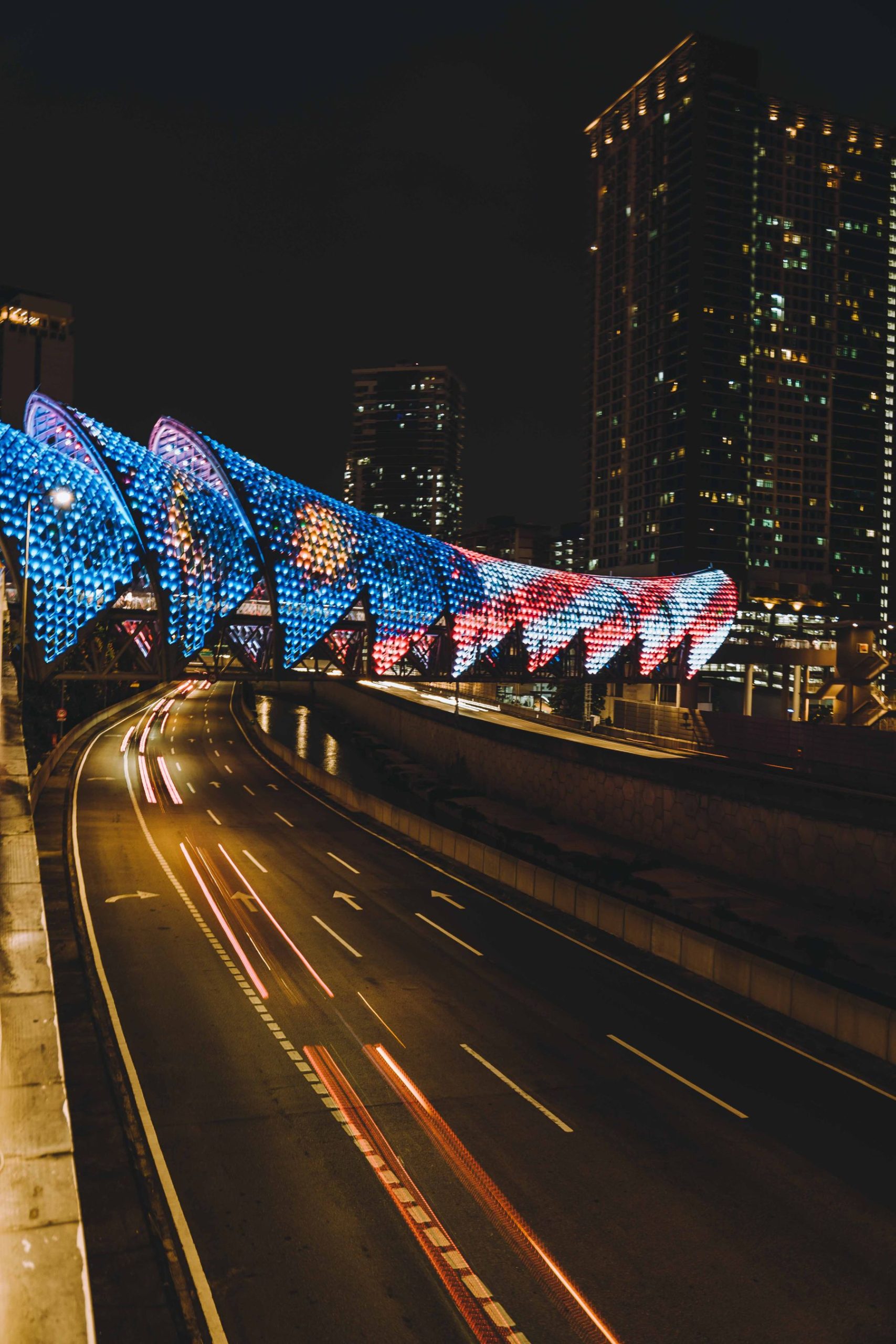 LED-lit Saloma Link bridge and light trails on the road below at night.