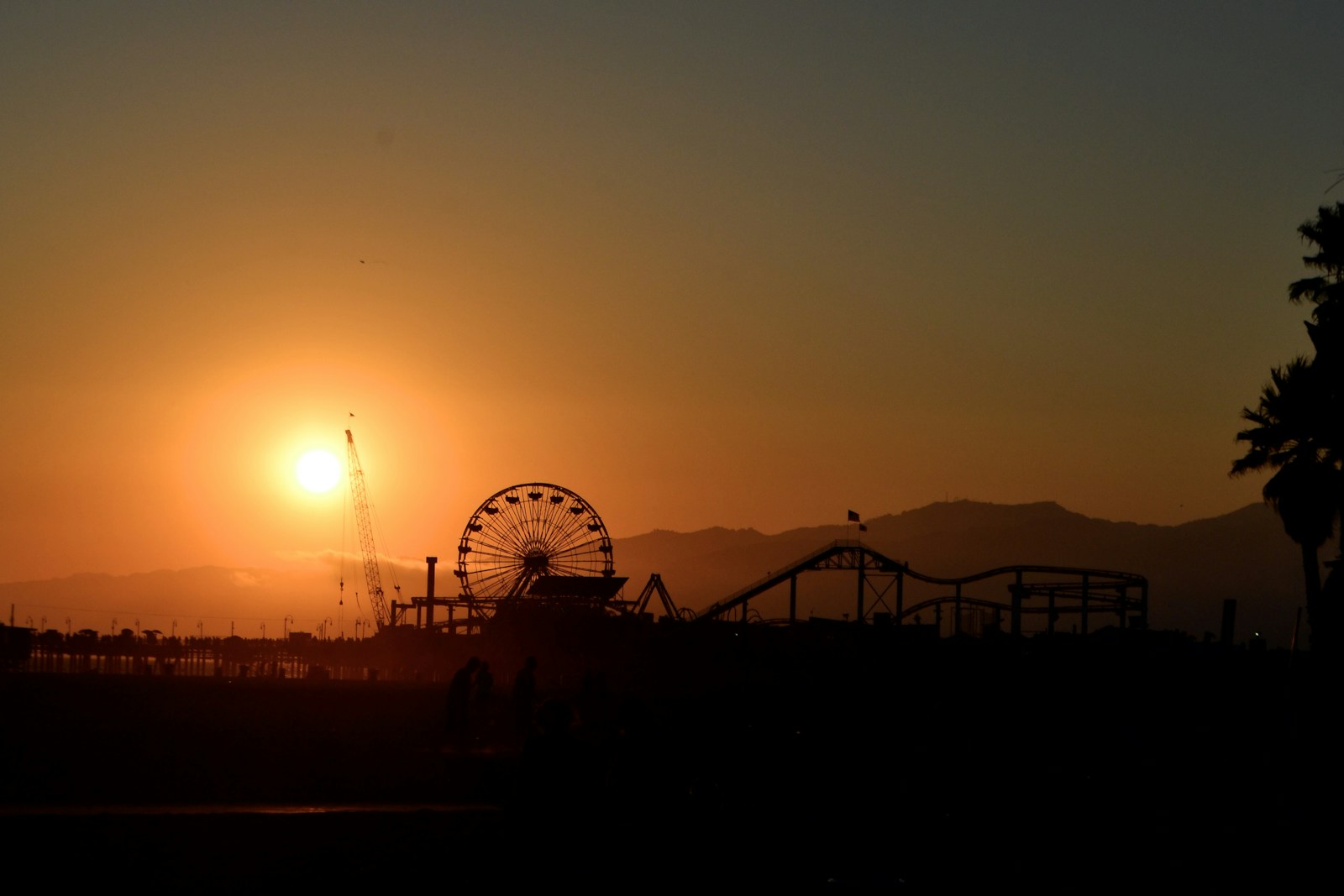 Santa Monica Pier Ferris wheel and roller coaster silhouetted at sunset