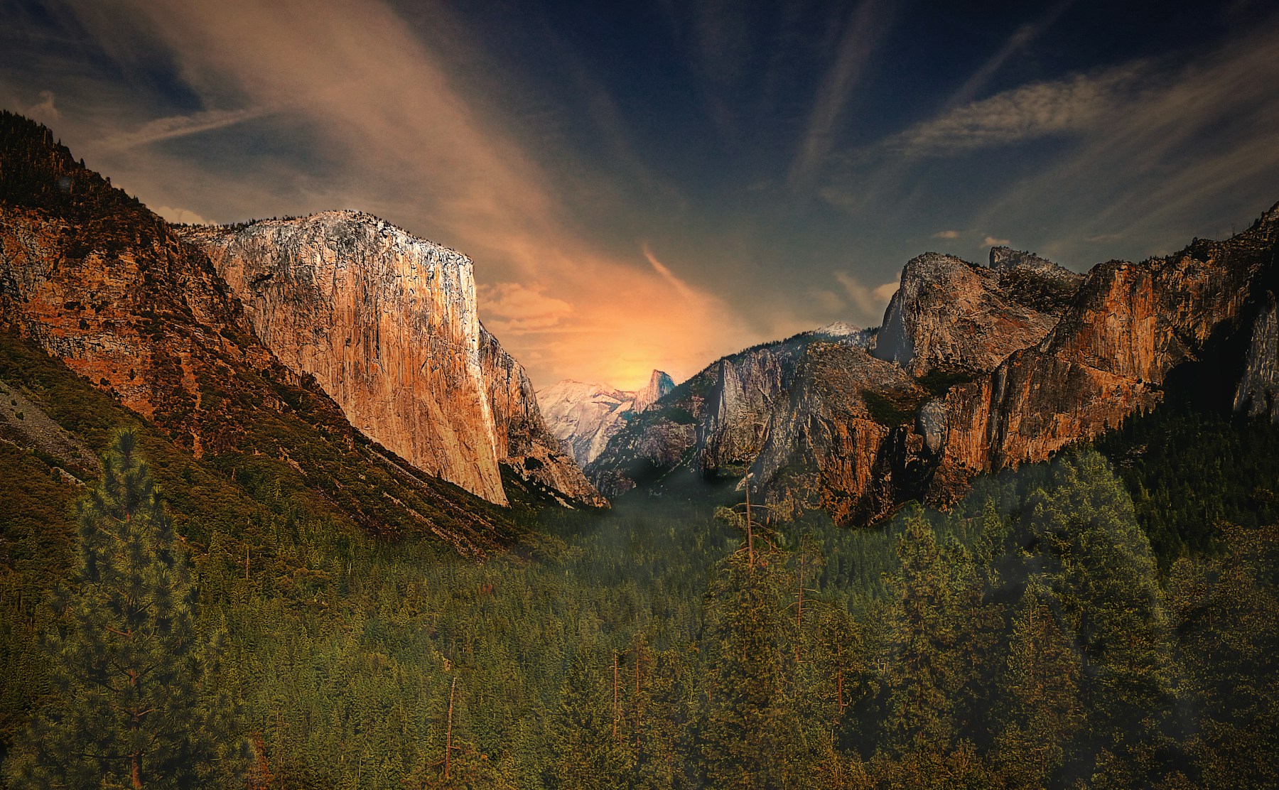 Sunset light on El Capitan and the cliffs above the forested Yosemite Valley