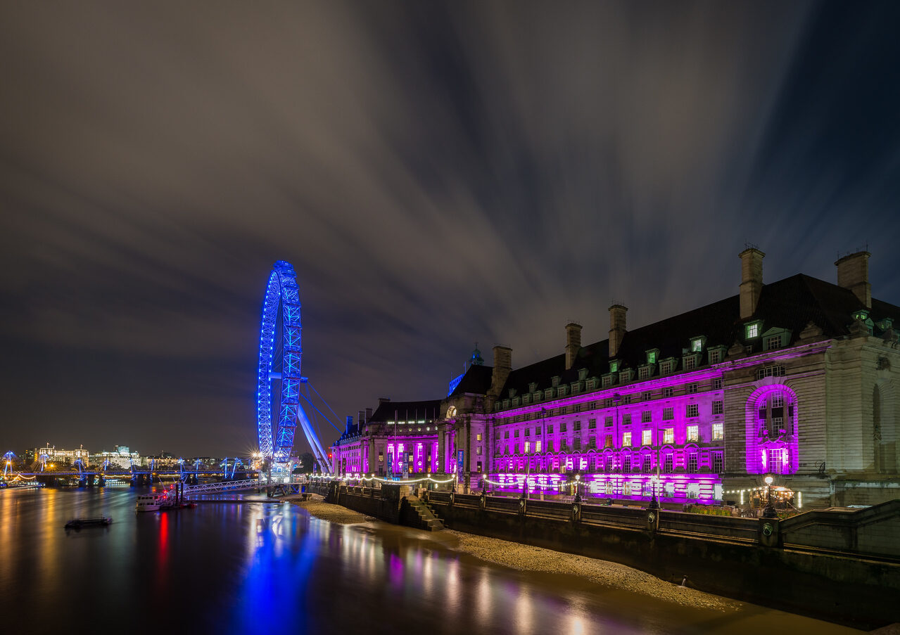 London Eye and illuminated County Hall reflected in the River Thames at night