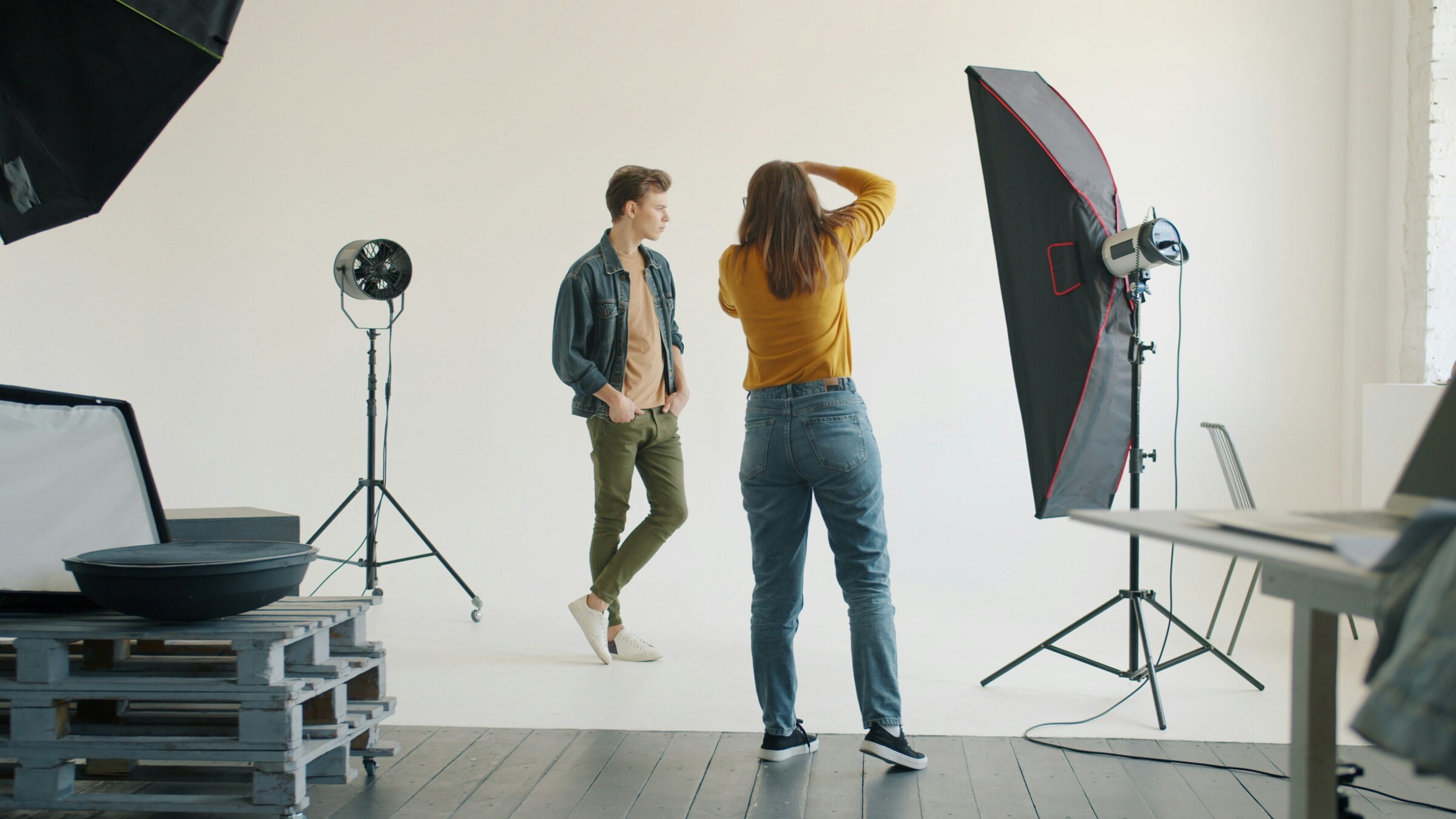 Photographer directing a standing model between studio lights and a large softbox