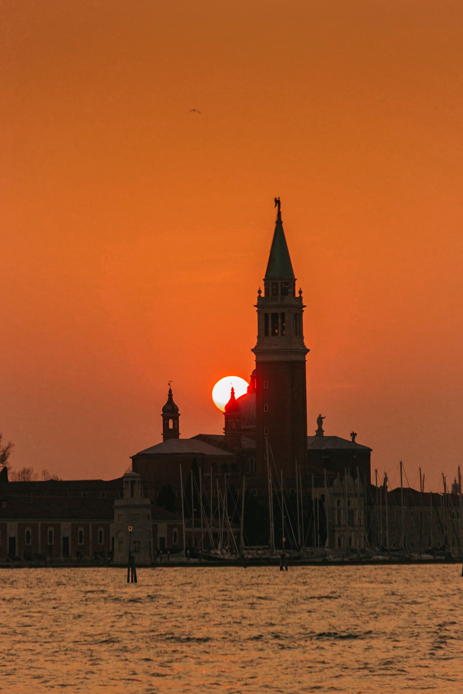 The bell tower and domes of San Giorgio Maggiore silhouetted against an orange Venetian sunset