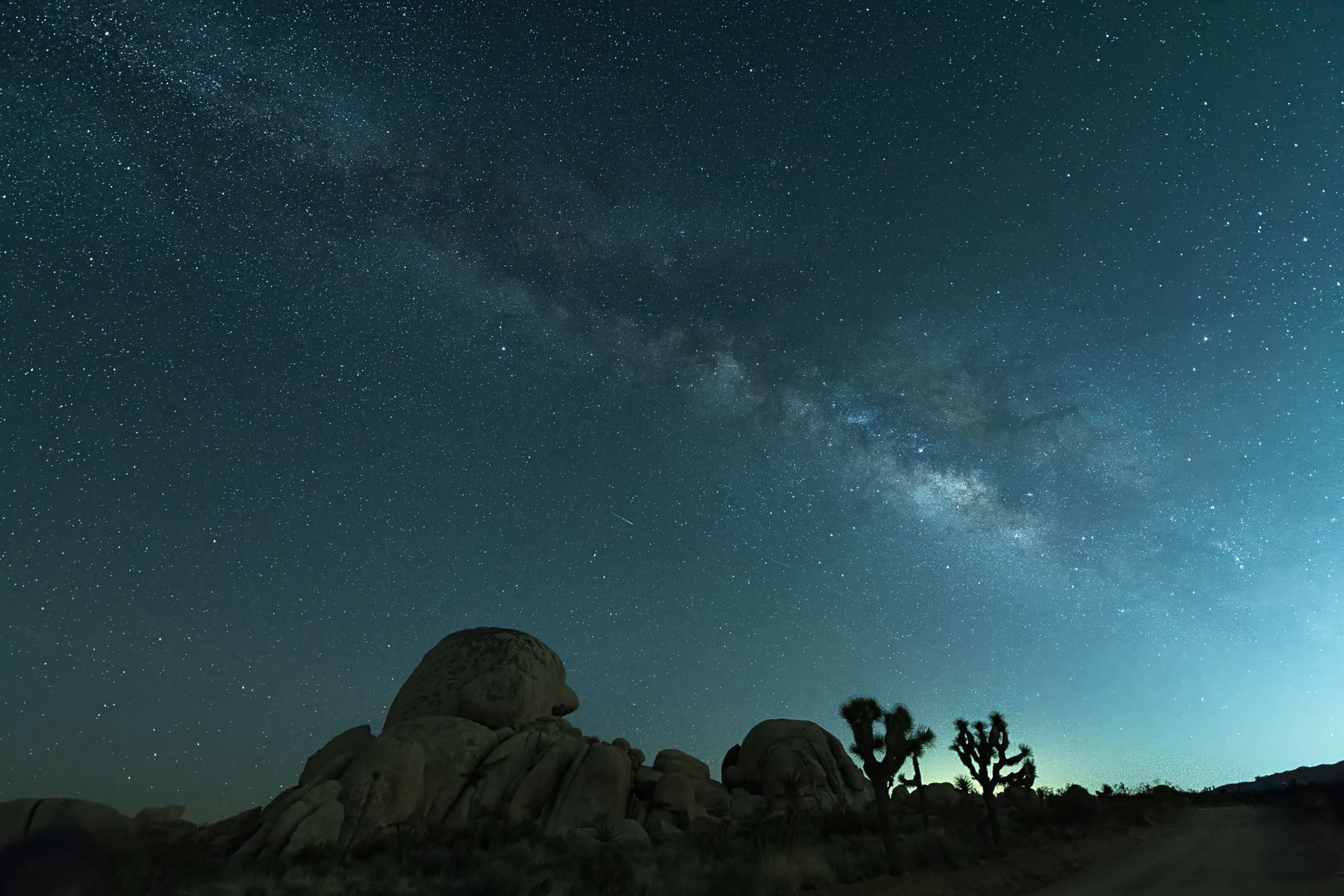 Milky Way over boulder formations at night in Joshua Tree National Park