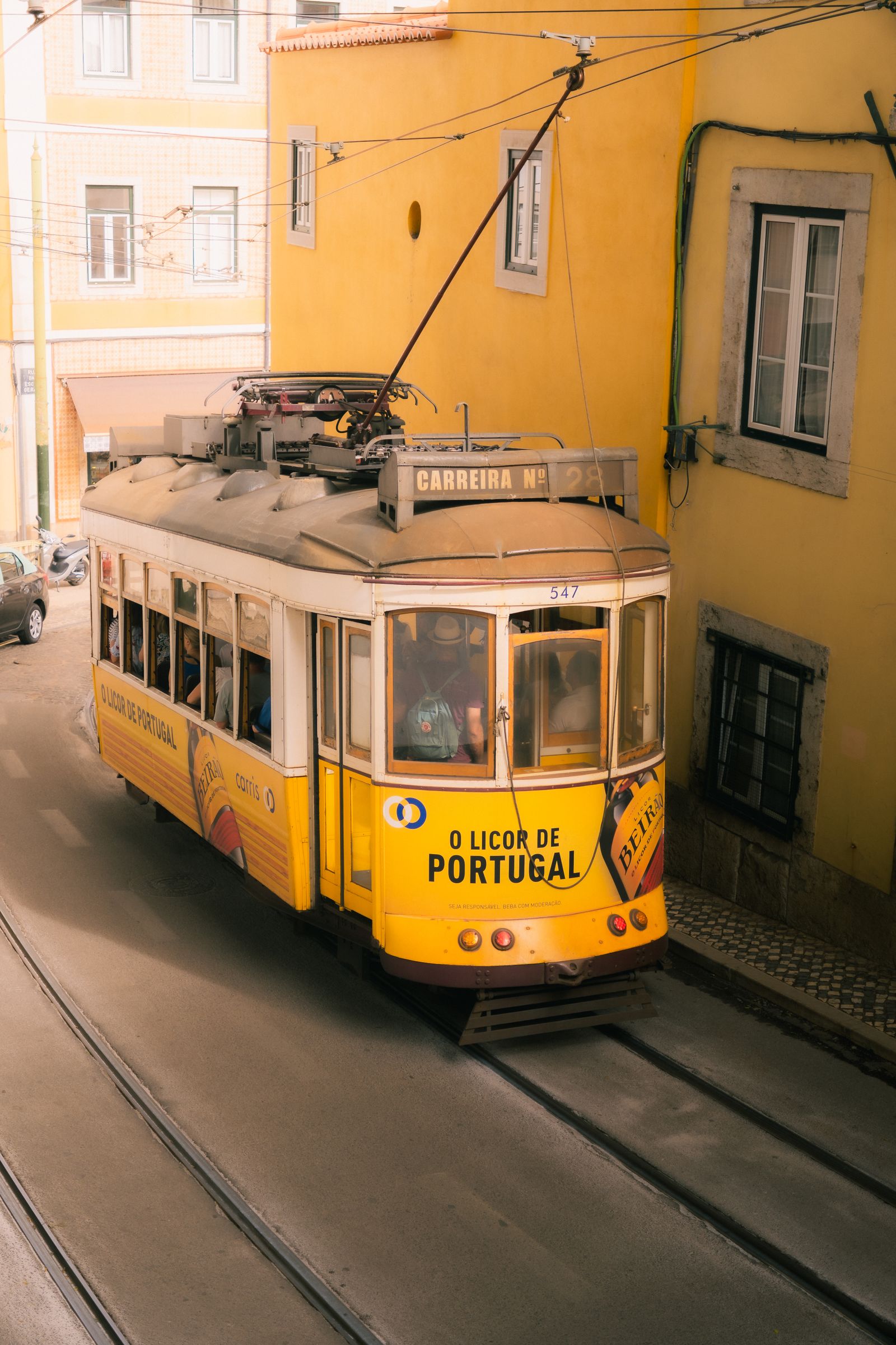 Yellow Lisbon tram passing through a narrow street in Alfama