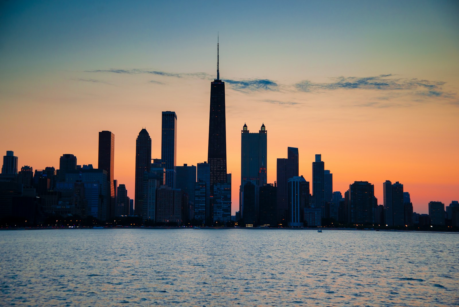 Chicago skyline silhouetted against an orange sunset across Lake Michigan
