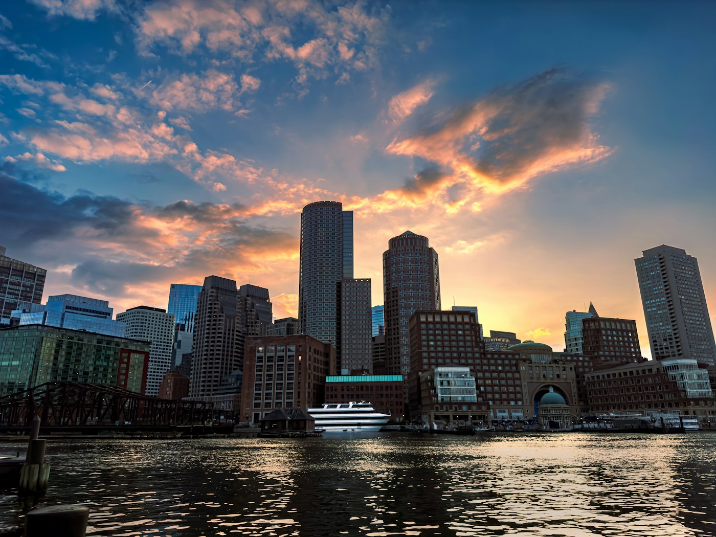 Boston waterfront skyline beneath a dramatic sunset sky, photographed from Fan Pier Park