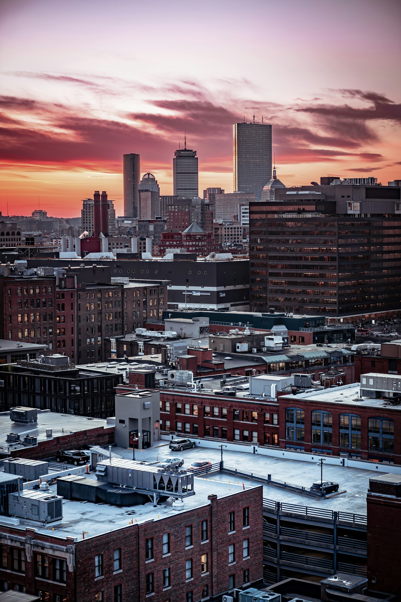 Boston skyline beneath pink sunset clouds, viewed across the rooftops