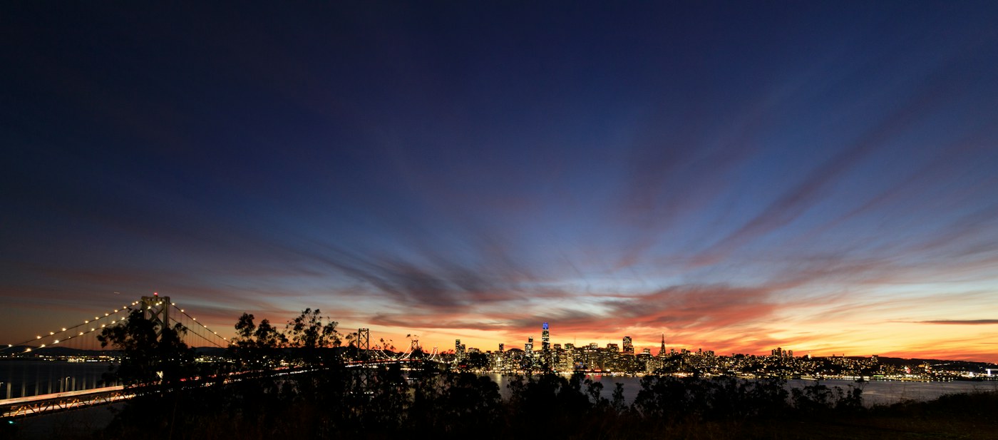 San Francisco skyline silhouetted against a fiery sunset over the Bay Bridge