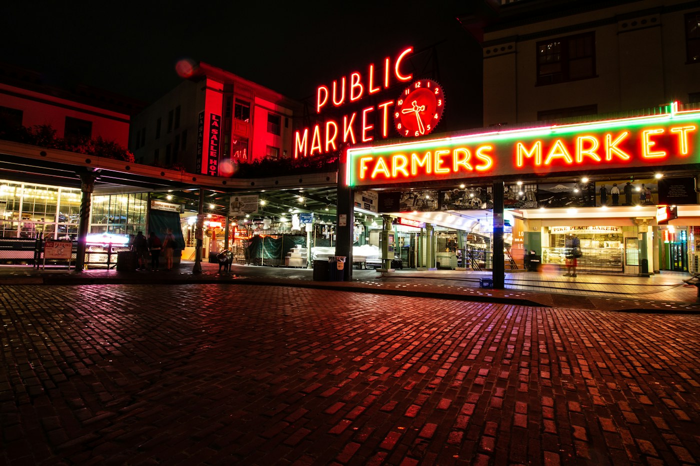 Pike Place Market neon signs reflected on wet cobblestones at night