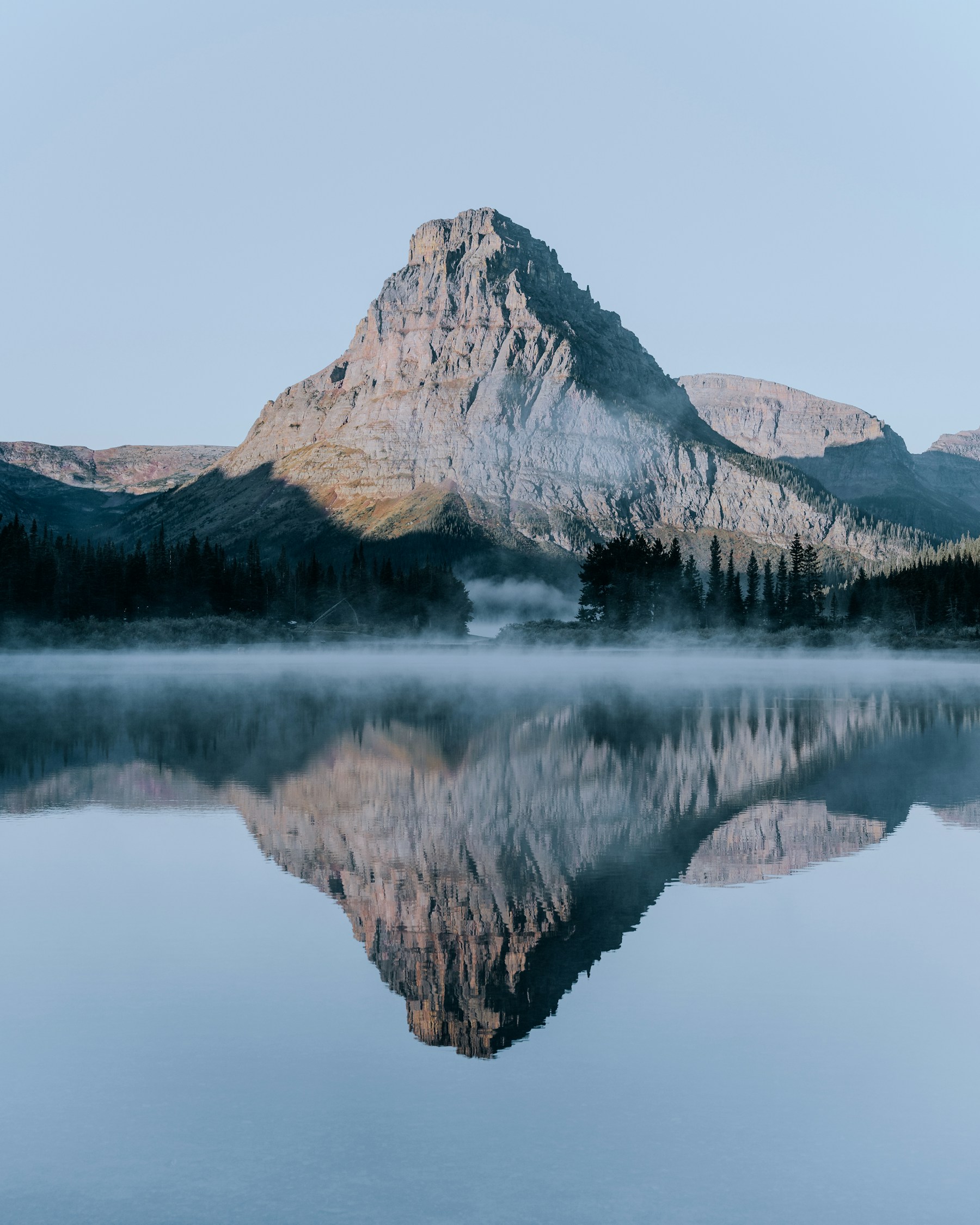 Mountain peak reflected in a misty lake at dawn in Glacier National Park
