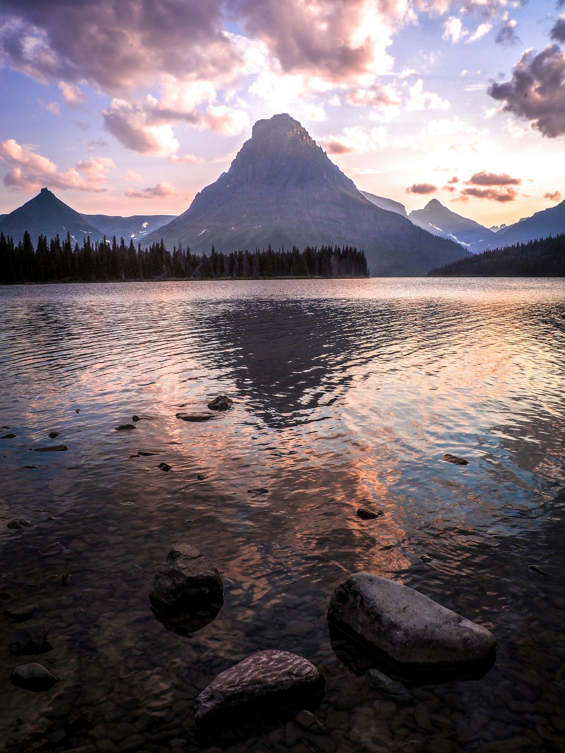 Two Medicine Lake reflecting pastel sunset clouds and a mountain peak