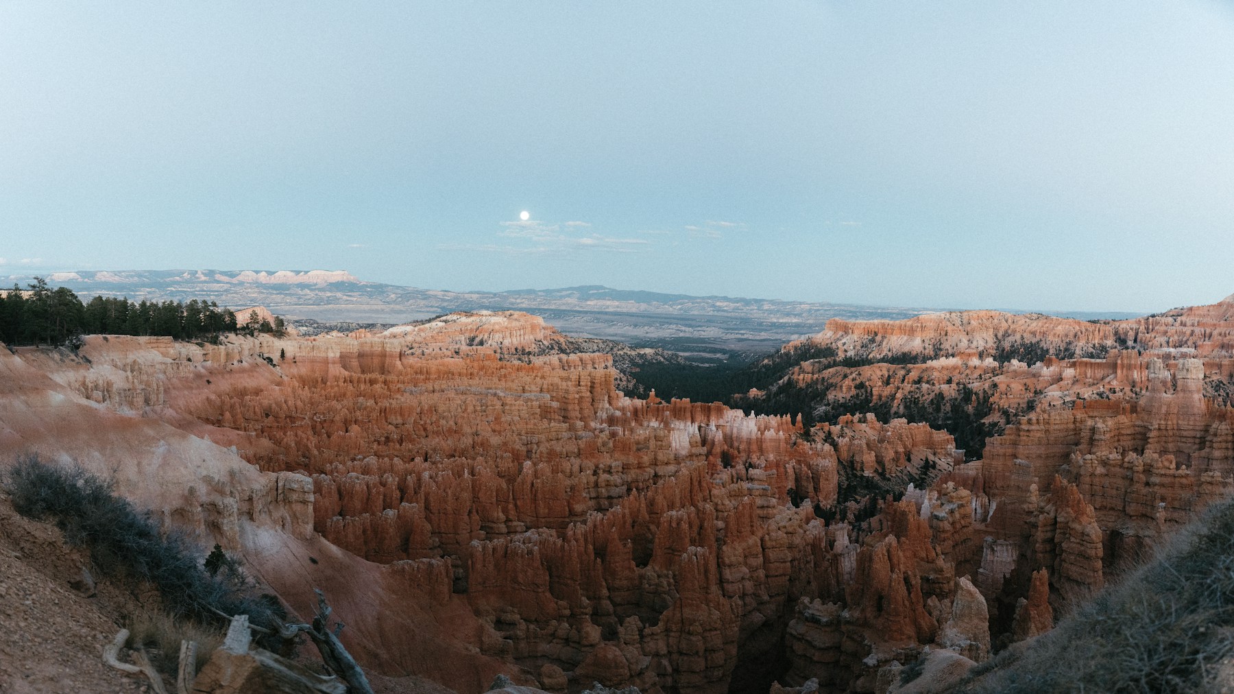 Moon rising over the orange hoodoos of Bryce Canyon National Park at dusk