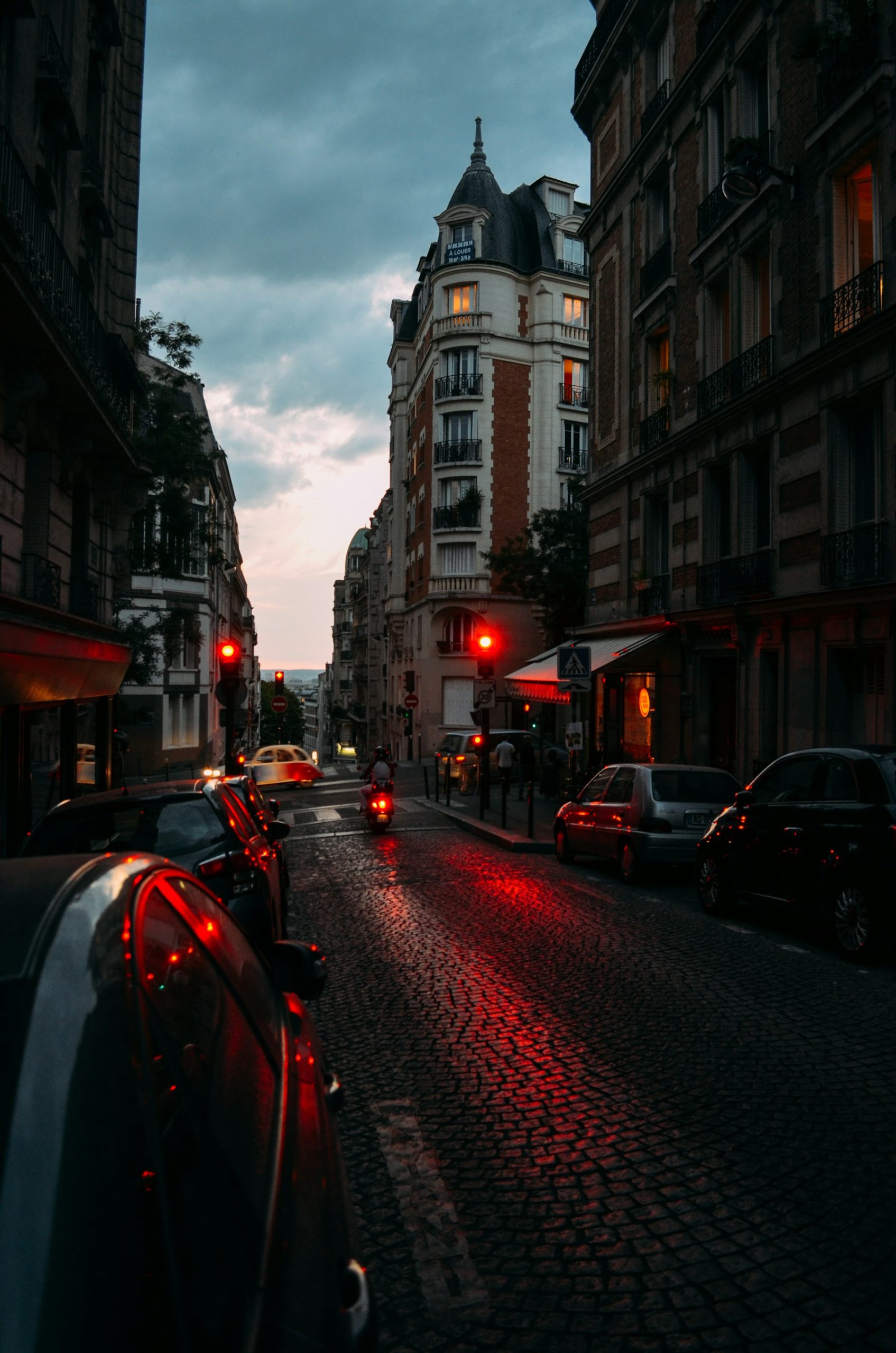 Paris street at blue hour with wet cobblestones and red traffic lights