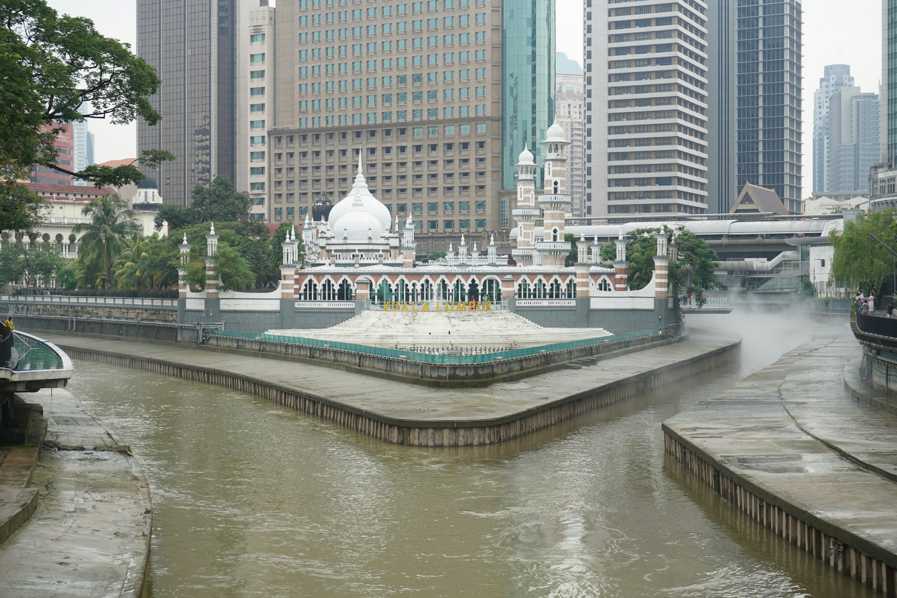 Masjid Jamek at the meeting of two rivers, with city buildings behind.