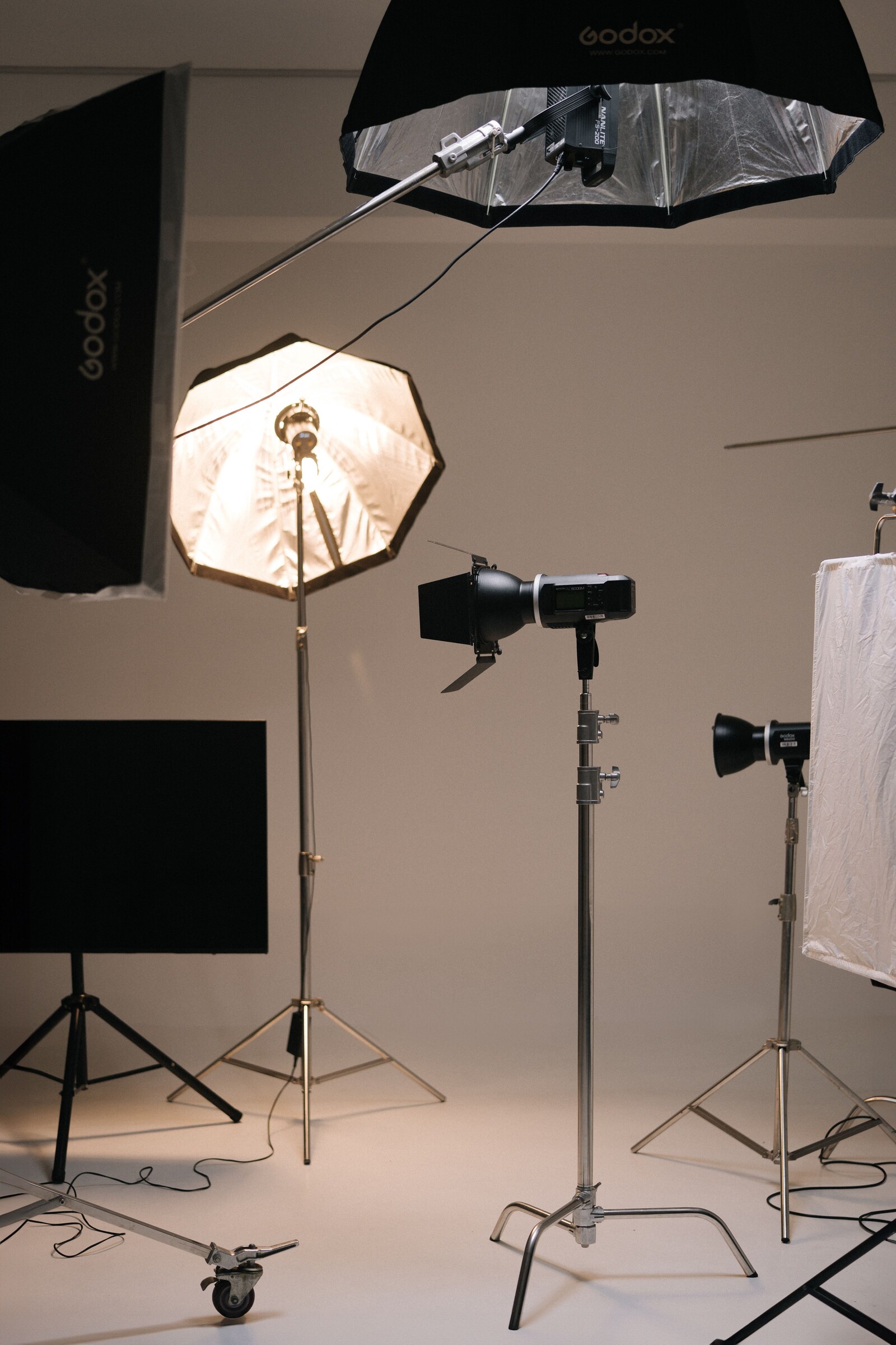 Studio strobes, softboxes, umbrellas and light stands arranged on an indoor shooting floor