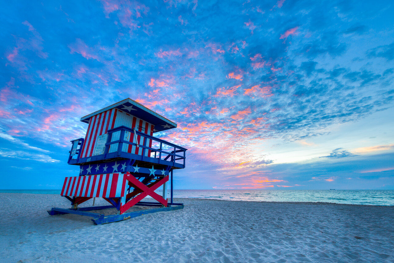 South Beach Miami lifeguard tower painted red white and blue beneath pink-blue sunrise