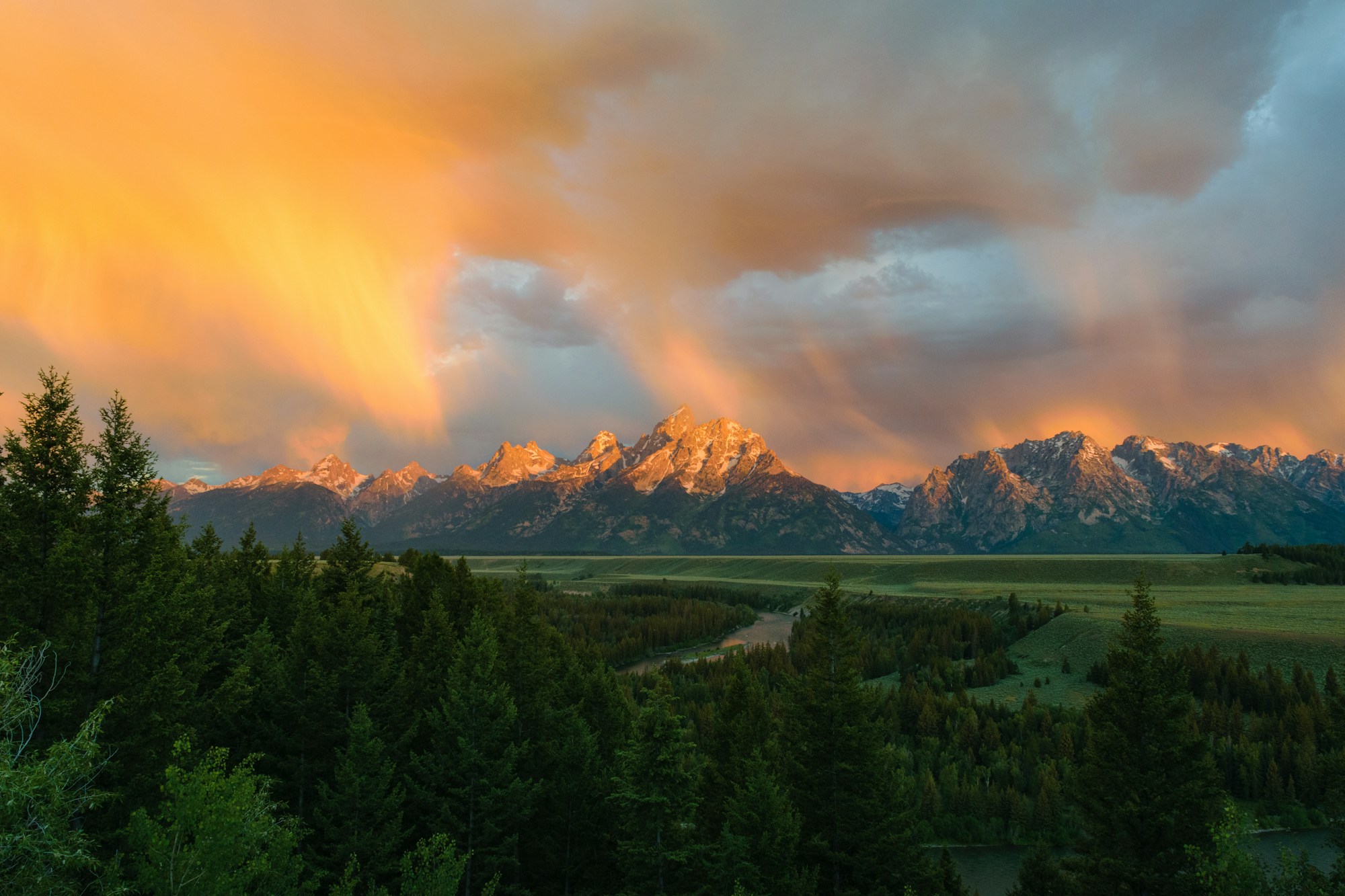 Orange sunset illuminating the Grand Teton range above the Snake River