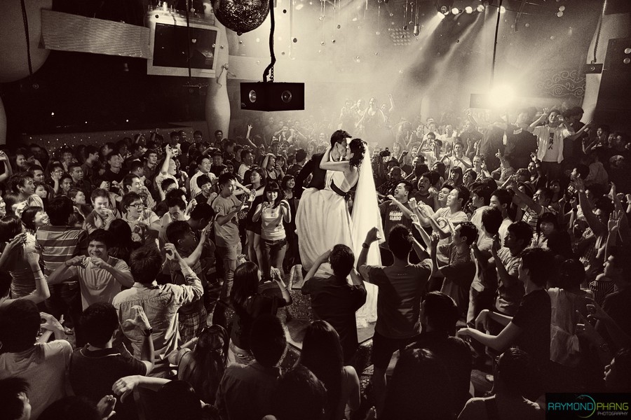 Black-and-white photograph of a couple surrounded by a cheering crowd.