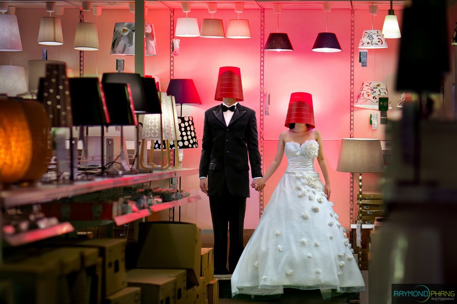Wedding dress and groom mannequin displayed in a pink-lit shop.