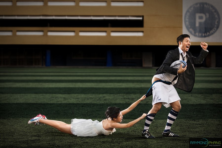 Man in a suit runs across a field while pulling a woman by the hand.