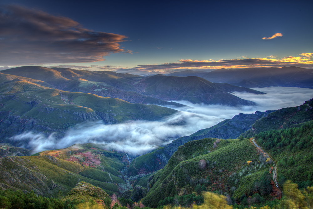 Green mountain valley in Galicia with bands of mist drifting through at sunrise
