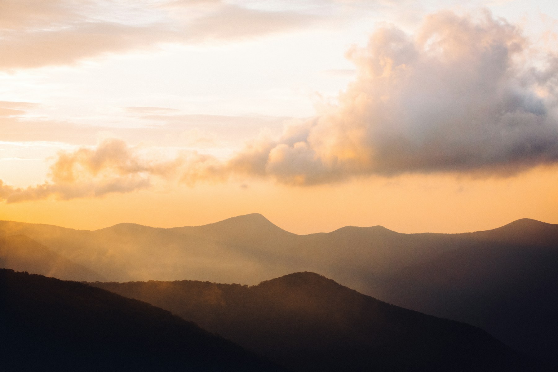 Golden sunrise over layered Blue Ridge mountains from a Parkway overlook near Asheville, North Carolina.