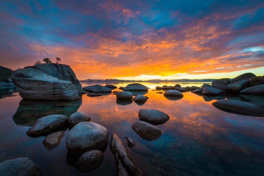 Bonsai Rock reflected in Lake Tahoe beneath orange and pink sunset clouds