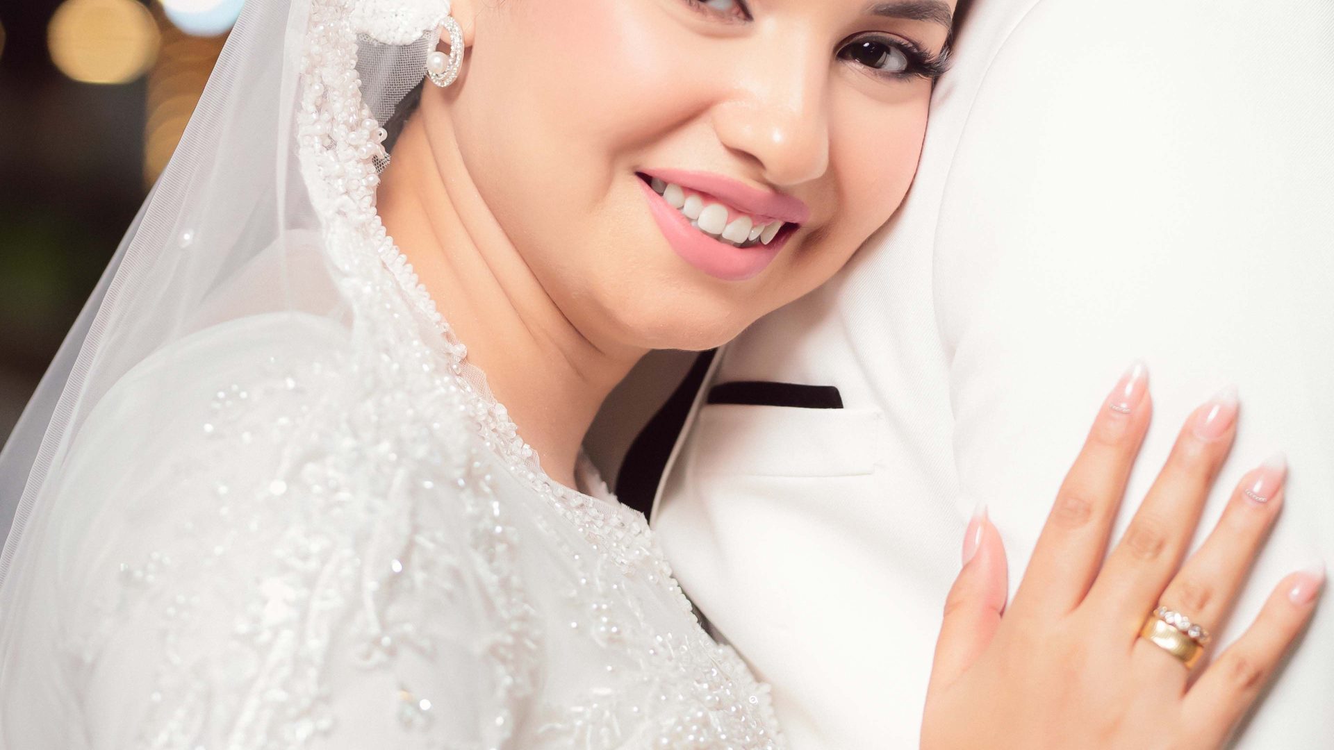 Smiling bride embracing the groom beneath blurred lights at night
