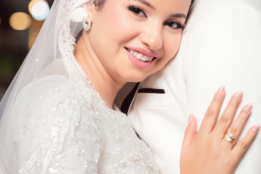 Smiling bride embracing the groom beneath blurred lights at night