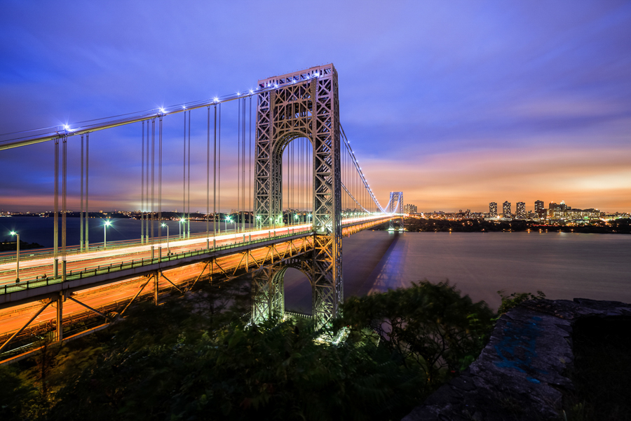 George Washington Bridge glowing at dusk above the Hudson River.