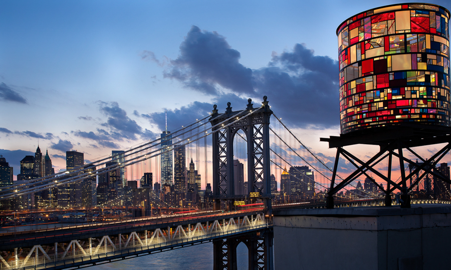 Manhattan Bridge and a colorful rooftop water tower at dusk.