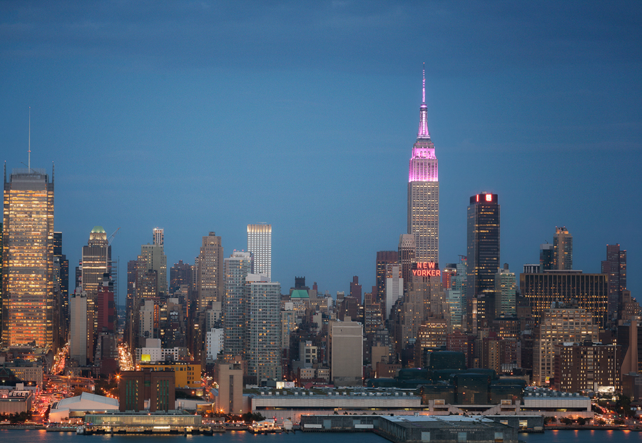 Midtown Manhattan skyline at blue hour with the Empire State Building lit pink.