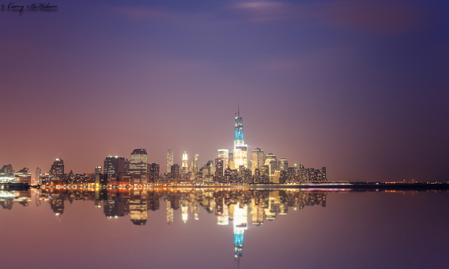 Manhattan skyline and its reflection in still water after sunset.