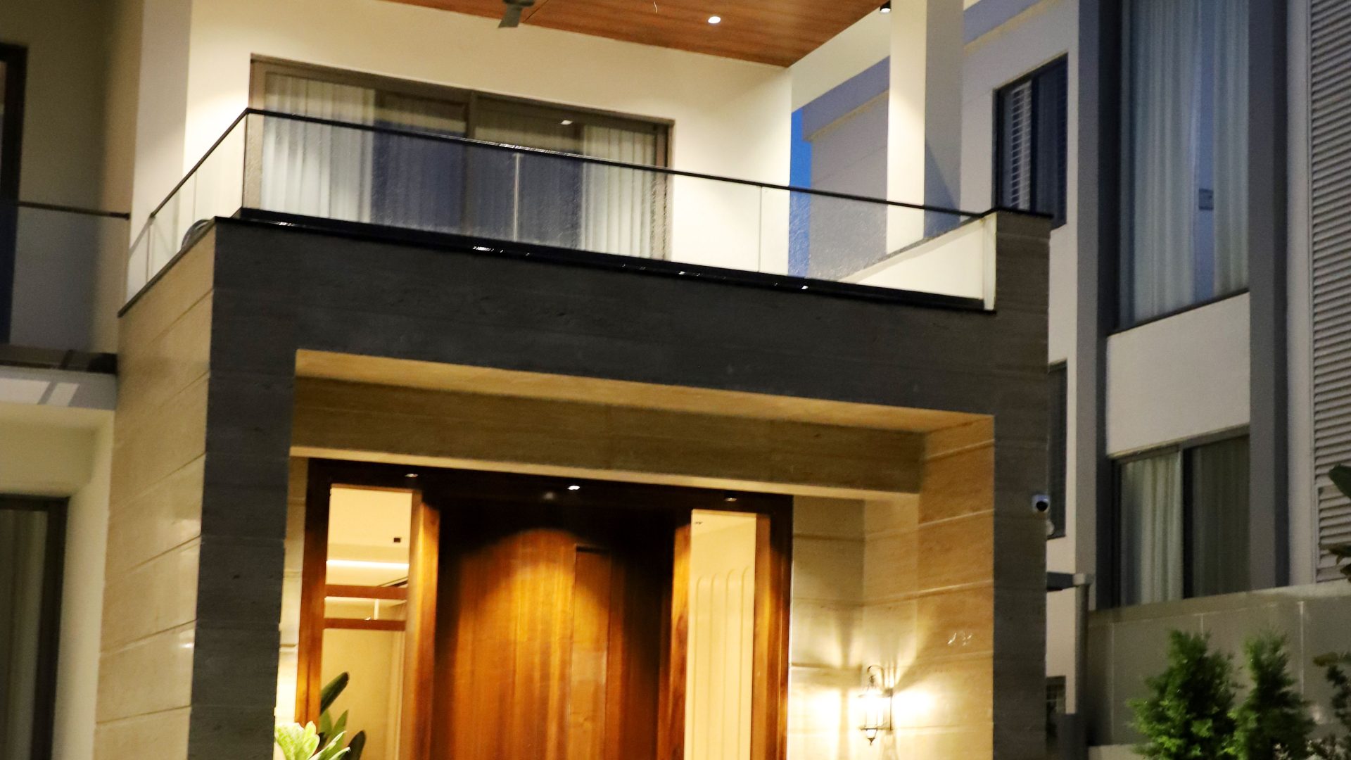 Contemporary house with illuminated entry and balcony at dusk