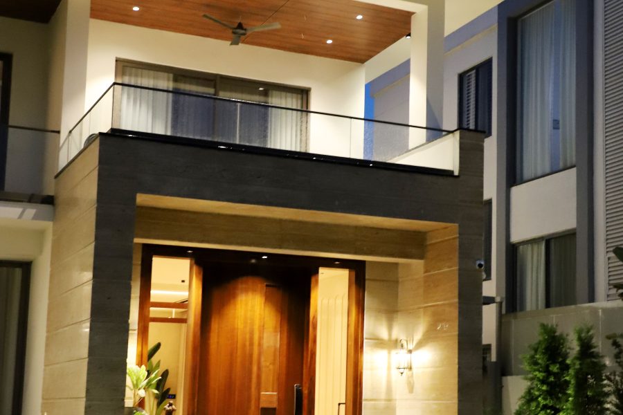 Contemporary house with illuminated entry and balcony at dusk