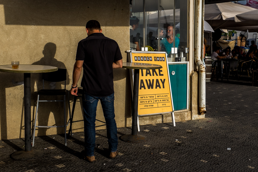 Man walks past a take-away restaurant with a bright yellow sign.