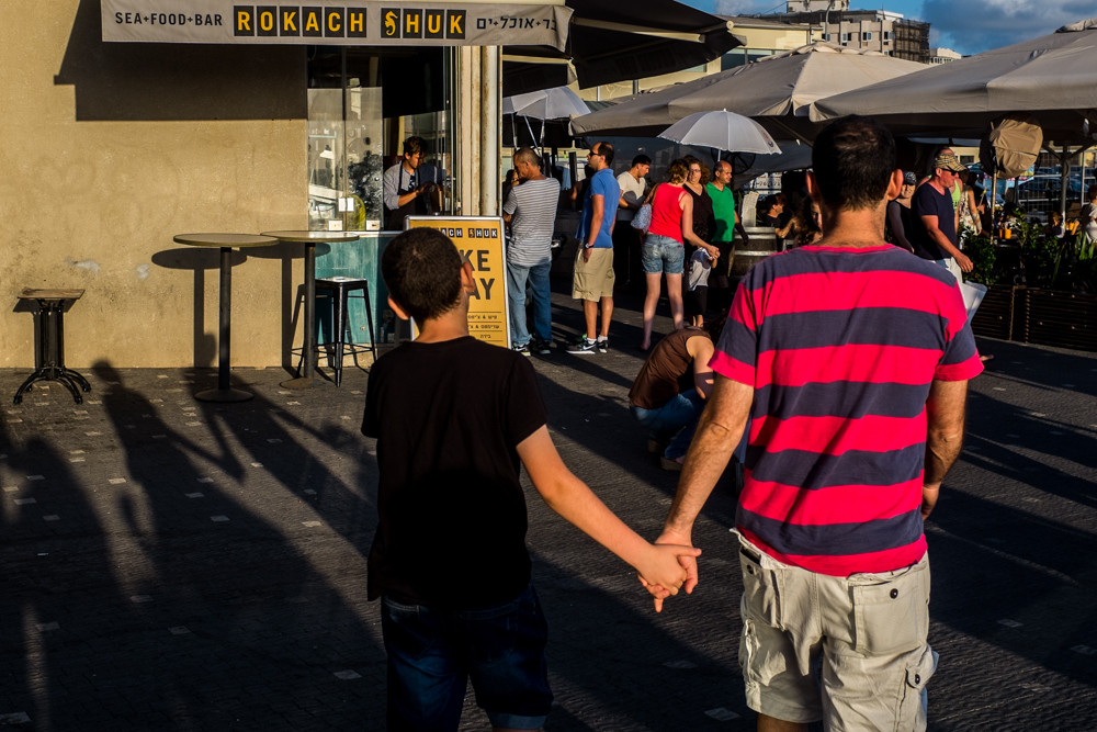 Two people walk hand in hand toward a busy take-away stand.