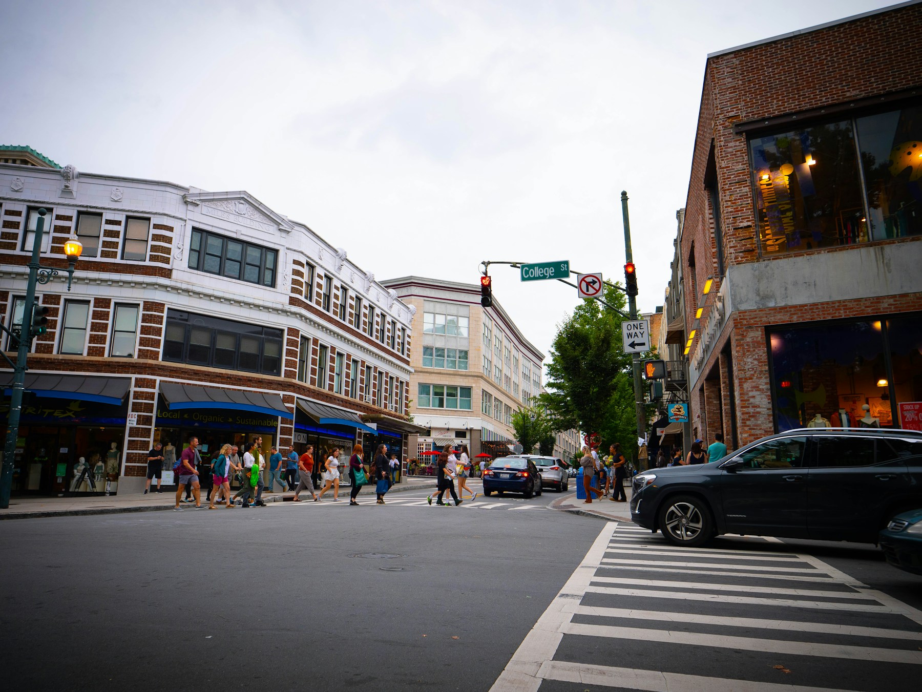 Pedestrians crossing College Street among downtown Asheville storefronts in North Carolina.