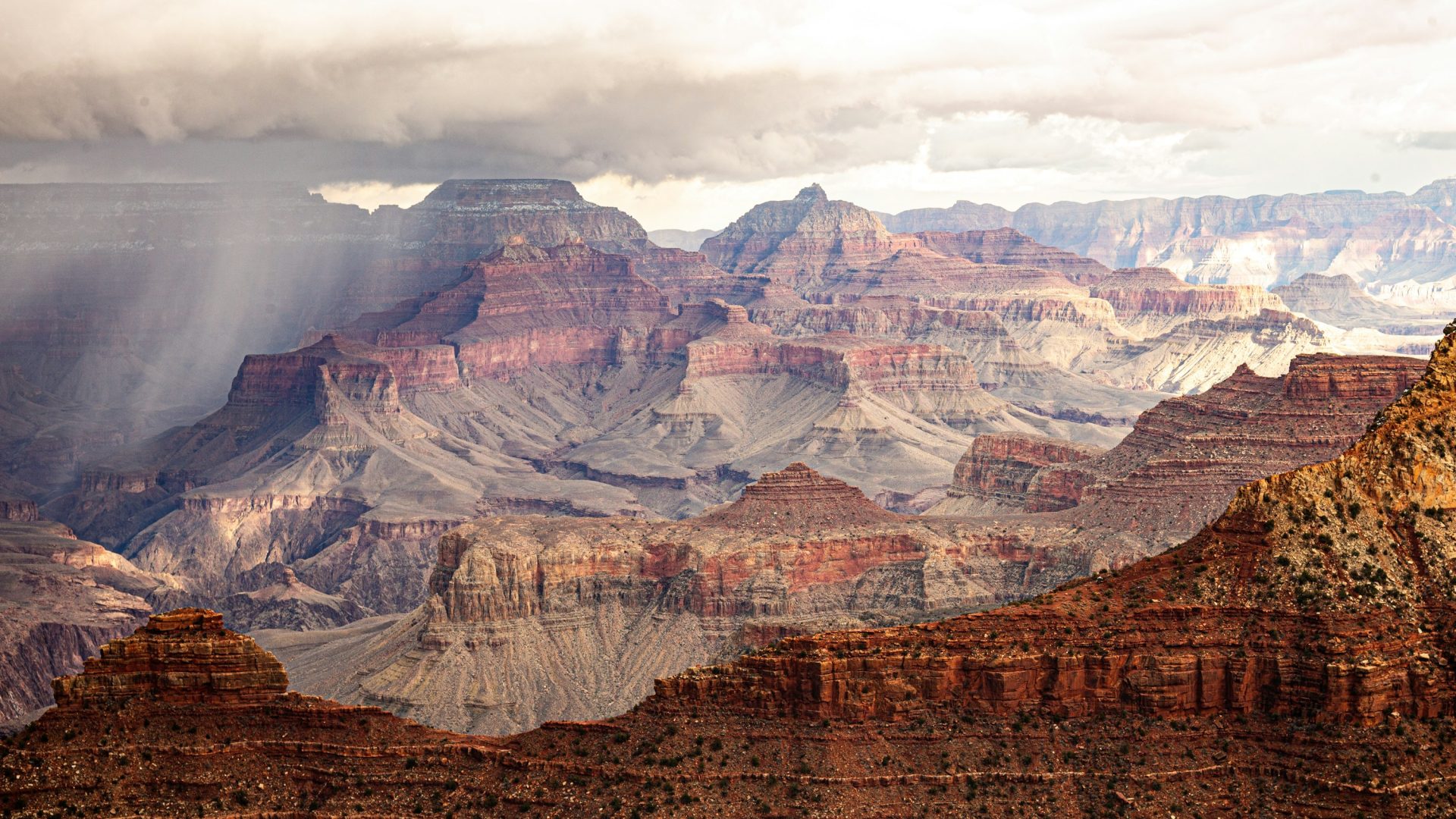 Sunbeams through clouds over layered Grand Canyon cliffs