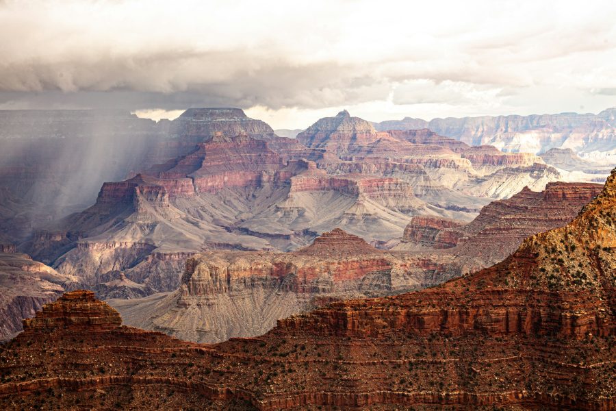 Sunbeams through clouds over layered Grand Canyon cliffs
