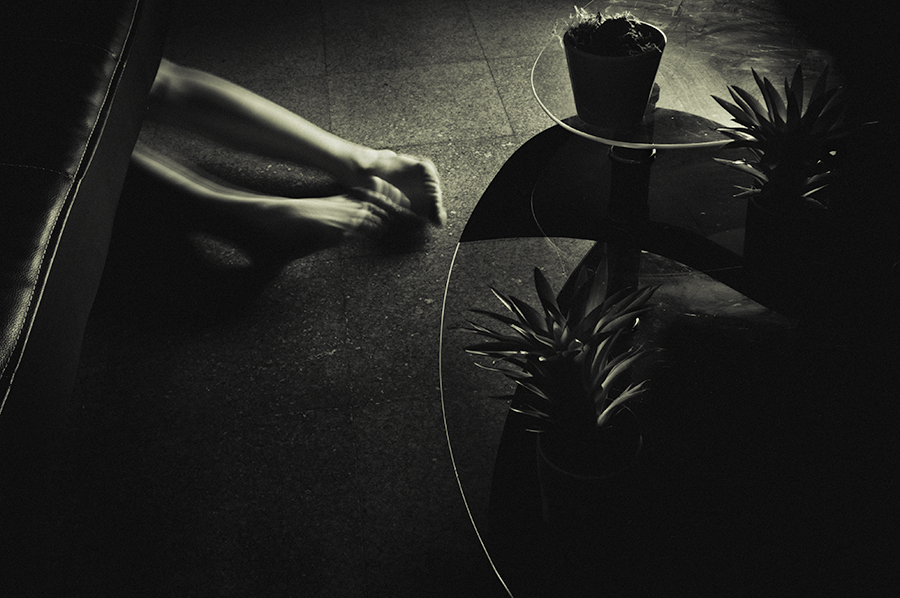 A blurred arm and hand beside a small round table holding a potted plant.
