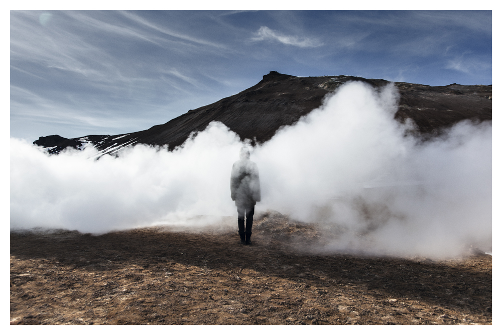 A person stands amid thick white steam rising from a barren mountainside - Pause by Juan Antonio Partal
