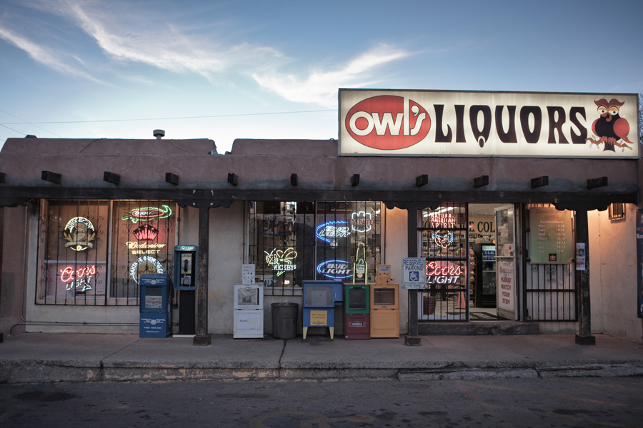 OWL Liquors storefront at dusk beneath a red and white sign.